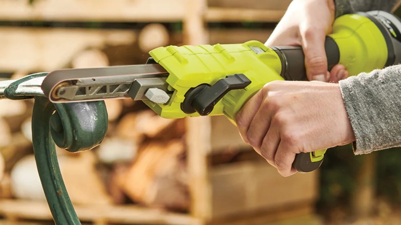 removing paint from bench with Ryobi belt sander