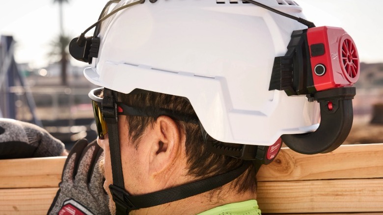 Person on a job site wearing a hard hat with a Milwaukee Bolt Cooling Fan attached