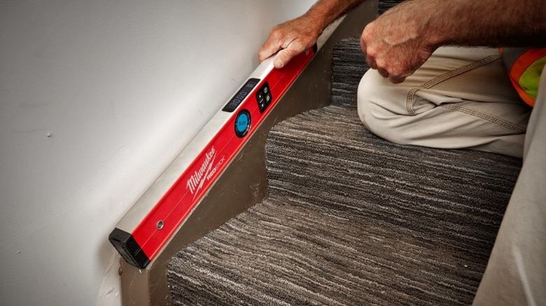 Person using Milwaukee Redstick Digital Level on a stairwell