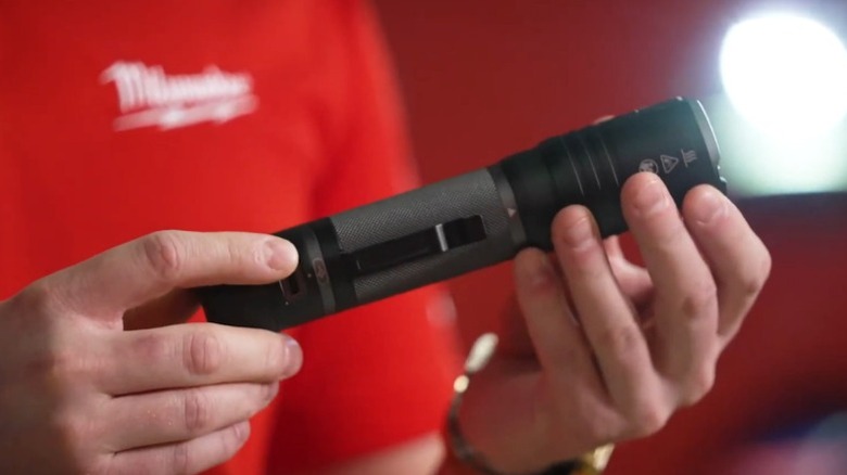 Person holding Milwaukee 2,000-lumen Slide Focus Flashlight