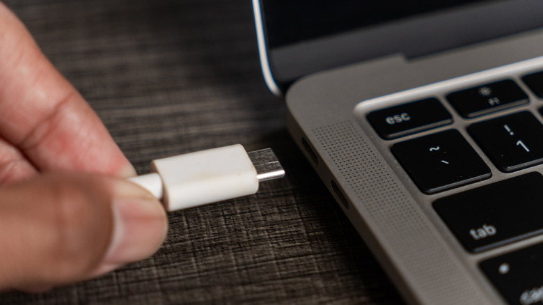 A hand plugging a USB-C cable into a laptop