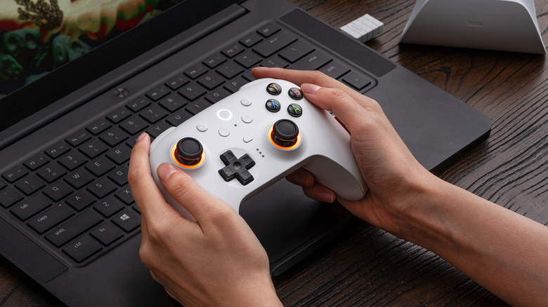 A person playing with the 8bitdo controller next to a laptop