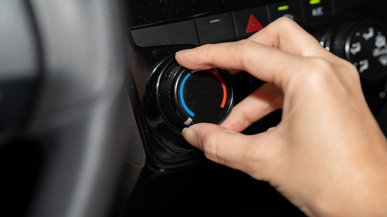 A hand manipulating AC controls in a car