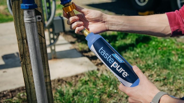 Person attaching a Camco Tastepure RV Water Filter to a water outlet.