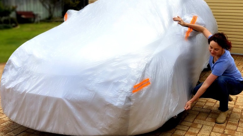 Woman placing EzyShade car cover on a car.