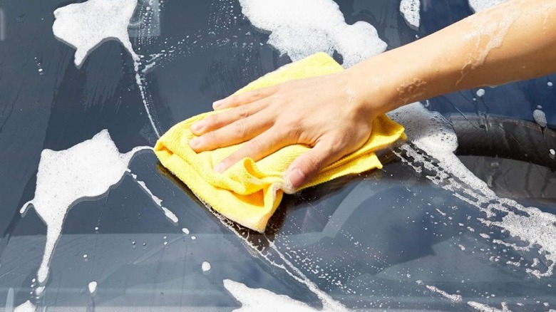 Wiping soapy windshield with yellow AmazonBasics microfiber cloth.
