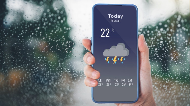 Woman using smartphone with weather app on screen