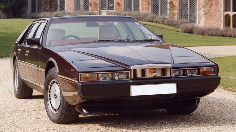 an Aston Martin Lagonda sitting on the gravel driveway of a country house