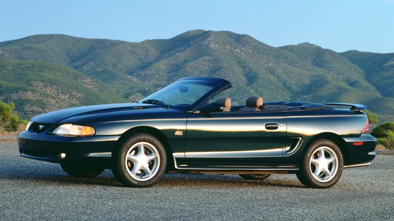 a 1994 Ford Mustang convertible parked on a gravel surface