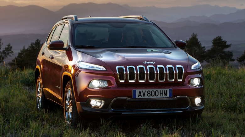 a red 2014 Jeep Cherokee parked on the grass