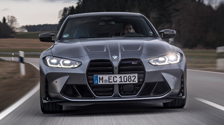 a gray 2021 BMW M3 Competition driving down a country road