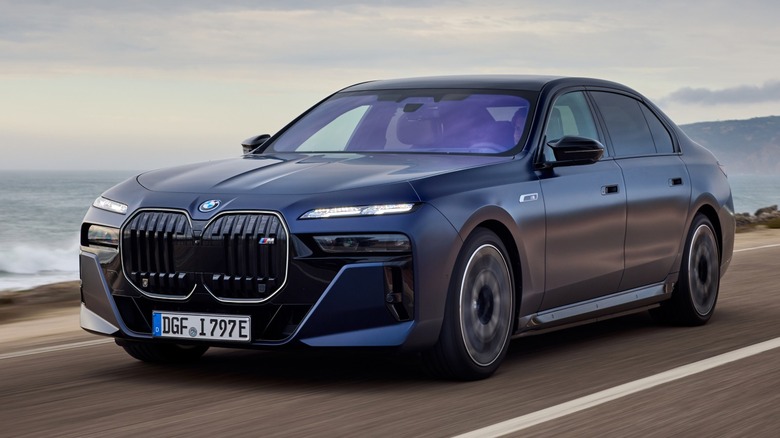 a blue 2023 BMW 7 Series driving down a coastal road