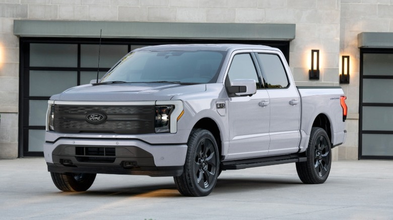 White 2025 Ford F-150 Lightning parked in front of a building.