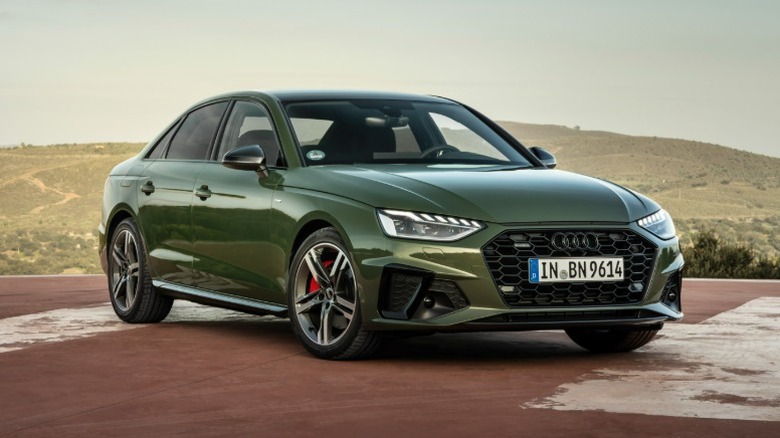 Green 2024 Audi A4 parked on a helipad with rural countryside in the distance.