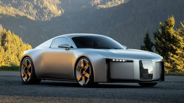 Silver Audi Concept C EV parked on a rural road with forested mountains in the distance.