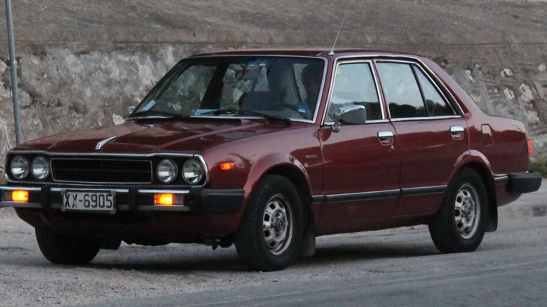 Honda accord from the 1970s driving on a dirt road