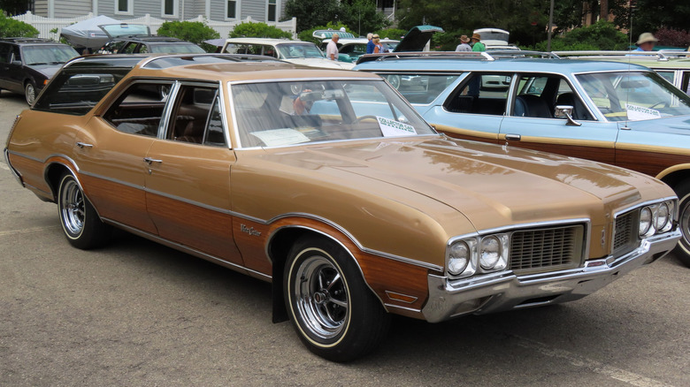 1970 Oldsmobile Vista Cruiser parked in a lot, featuring an earthy 70s brown color and wood paneling.