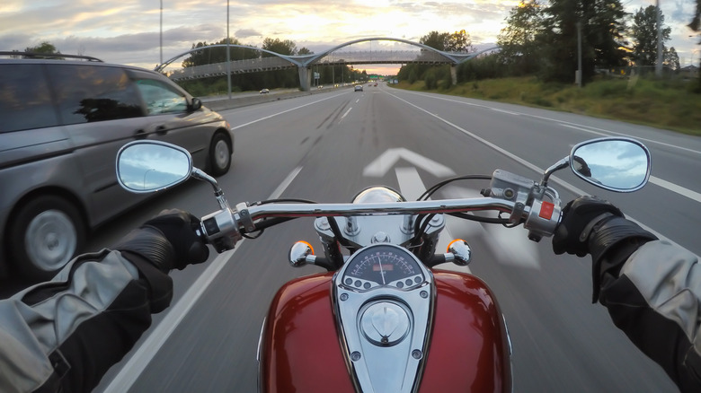 Motorcycle driver POV riding on road, minivan to the left.