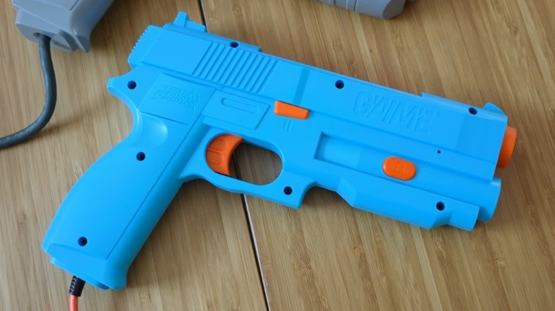 Blue G'aim'e light gun on a wood surface