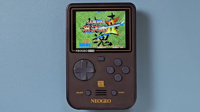 Super Pocket Neo Geo Edition handheld console on a blue surface with "Samurai Showdown II" playing