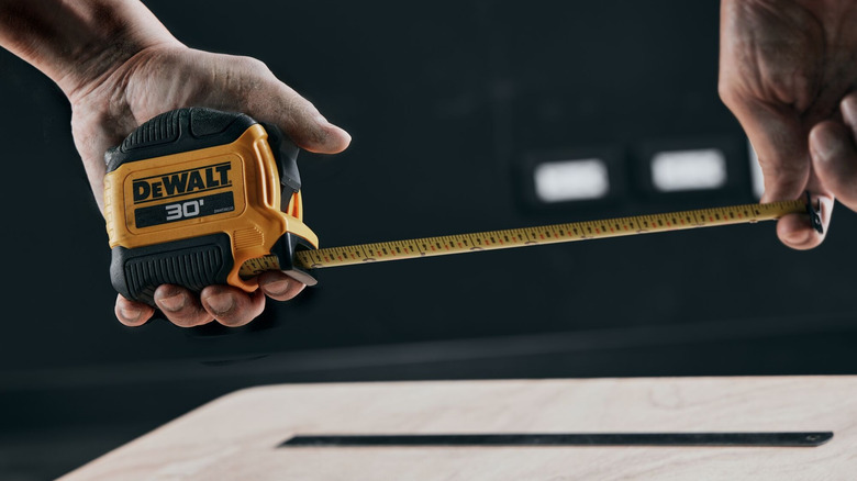 A worker pulling out several inches of a DeWalt tape measure