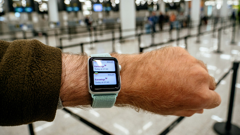 A person using their Apple Watch at the airport with boarding passes