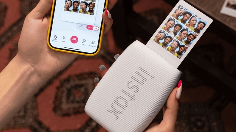 Woman printing a photo from smartphone using a wireless small printer