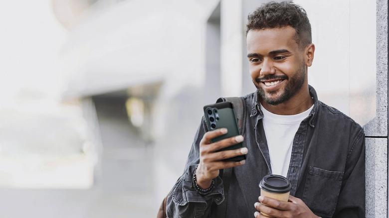 A smiling man holding an Android smartphone