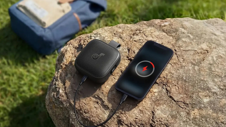 A speaker charging a phone on top of a rock