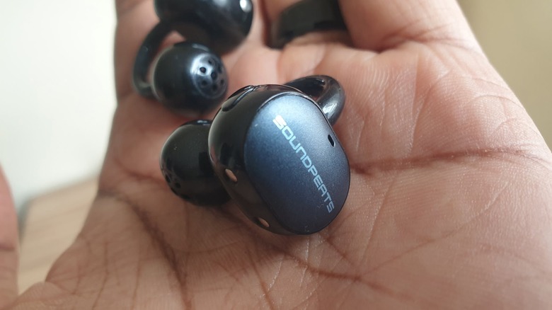 Person holding a pair of cip-on earbuds in the palm of their hand