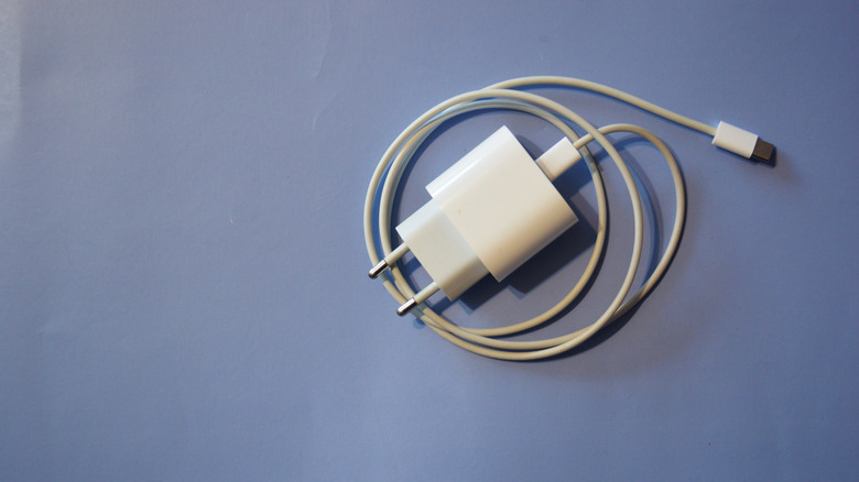 A nondescript white charging brick with cable wrapped up and lying on the floor