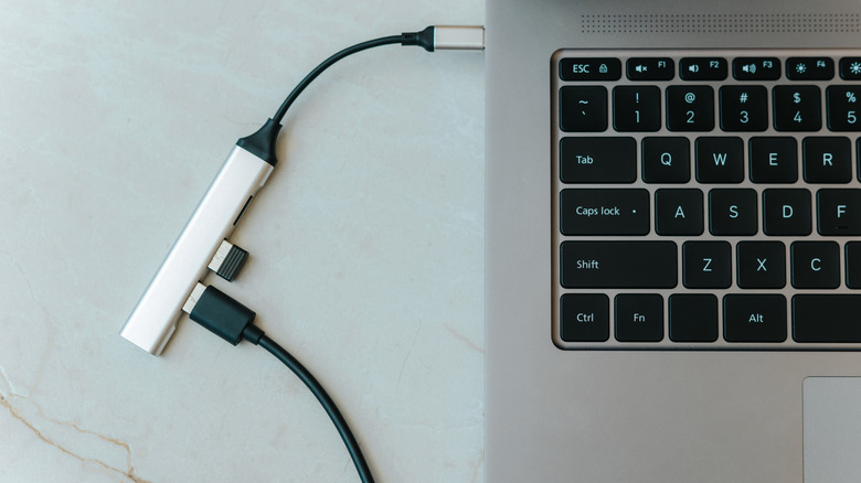 A USB hub dongle sticking out of the side of a laptop