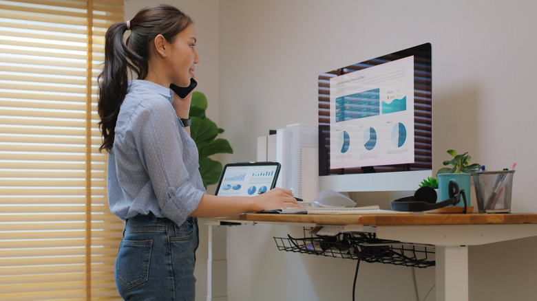 A woman working at a standing desk in a home office