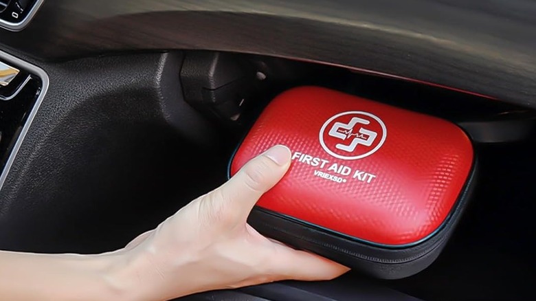 A first aid kit being grabbed from a glove compartment in a car.