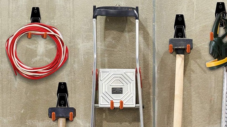 A ladder and other tools hung on the wall of a garage.