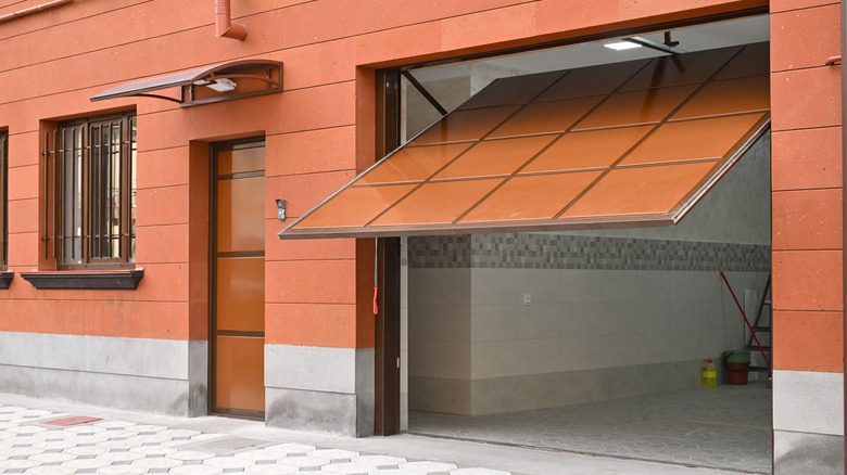 An automated garage door is open, revealing a garage with a ladder leaning against the wall.