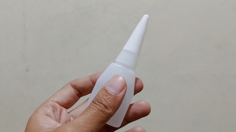 a bottle of super glue in the hand of one person