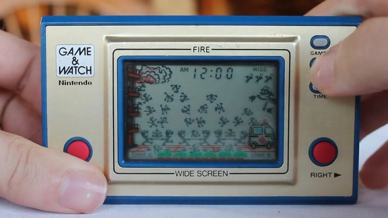 A Person playing the Nintendo Game & Watch Fire handheld LCD game