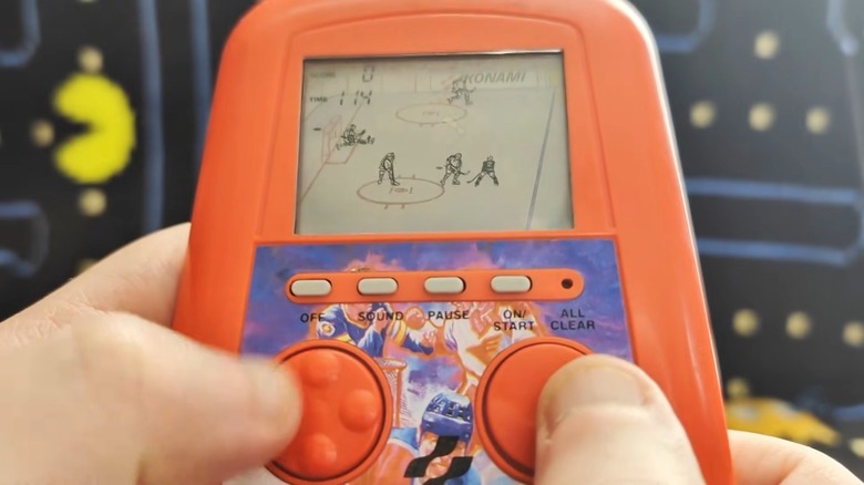A person playing the Konami Blades of Steel LCD handheld game