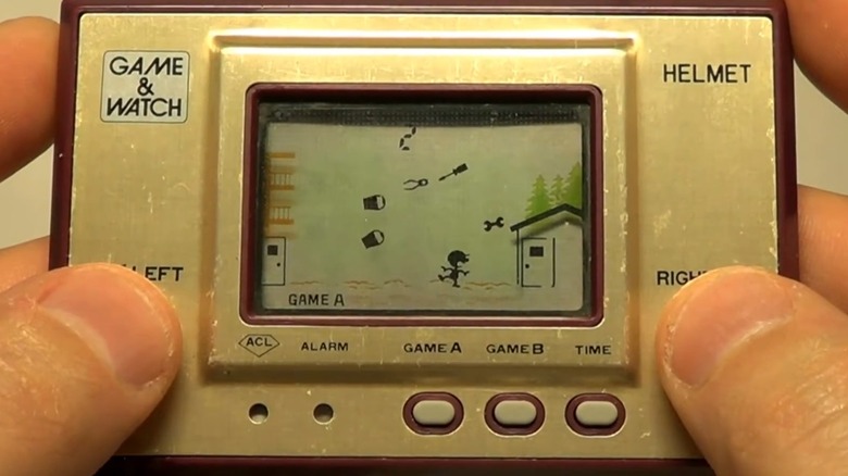 A person playing the Nintendo Game & Watch Helmet handheld game