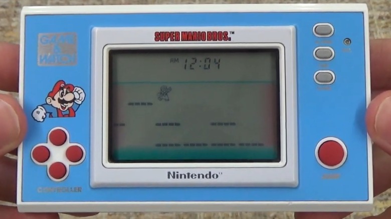 A person playing the Nintendo Game & Watch Super Mario Bros. handheld game