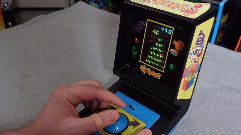 A person playing the Parker Bros. Q*Bert handheld game