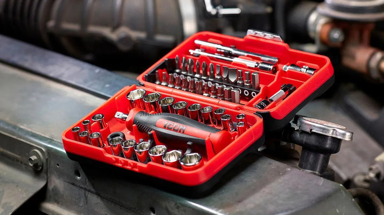A red Drive Compact Socket and Bit Set being used on an engine