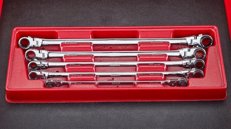 A red Extra-Long Professional Metric Double Box Flex Ratcheting Wrench Set on a black leather surface