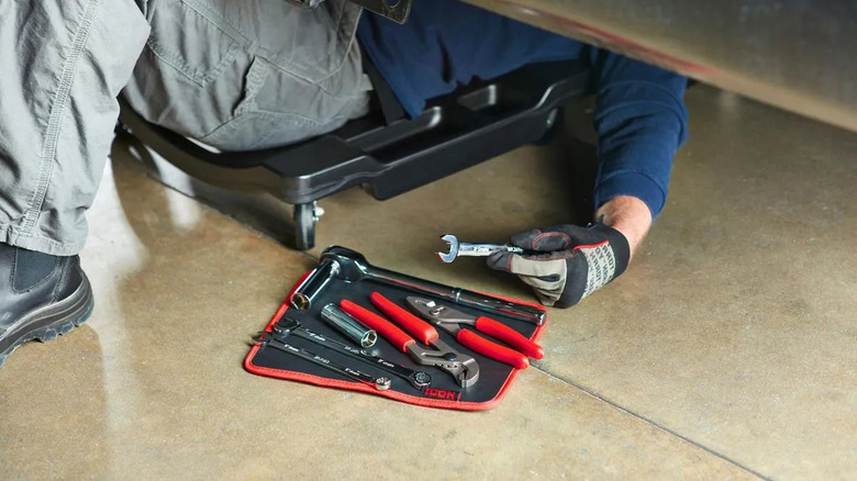 A person using tools while reaching out to a set placed on a Large Magnetic Tool Pad