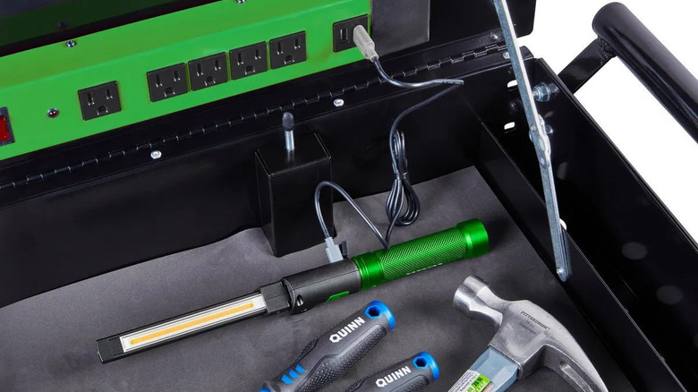 A person charging a LED Rechargeable Magnetic Handheld Foldable Slim Bar Work Light by plugging it into the USB slot of a green multiplug