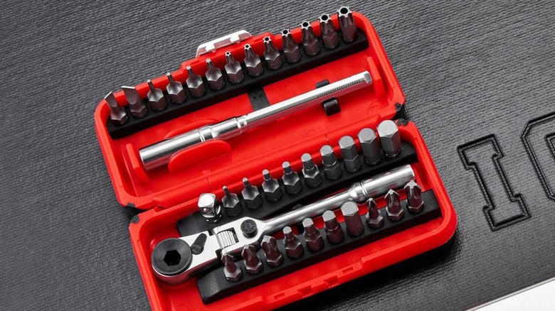 A red Locking Flex-Head Ratchet and Bit Set placed on a black surface with a leather texture