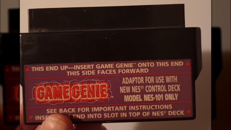 A hand holding the Game Genie Top Loader Adaptor