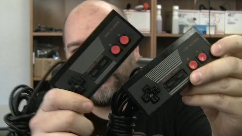 A man holding up two Sharp Game Television Controllers