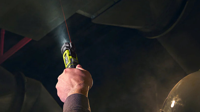 Worker using a Ryobi pivoting flashlight with laser showing